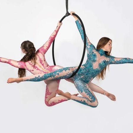 Zwei Akrobaten in prächtiger Performancekleidung zeigen deren Skills an einem gemeinsamen Hoop