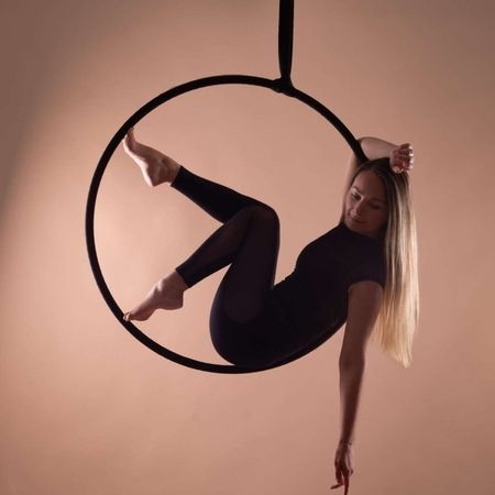 Performerin sitzt in einem Aerial-Hoop